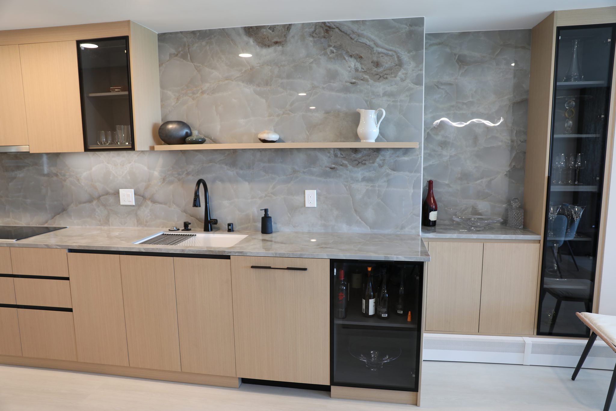 Sink, wine fridge, and glass cabinets against the stone backsplash