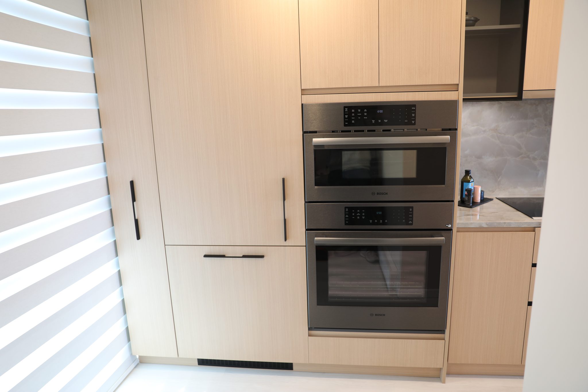 Stacked Bosch wall ovens in the oak cabinet run