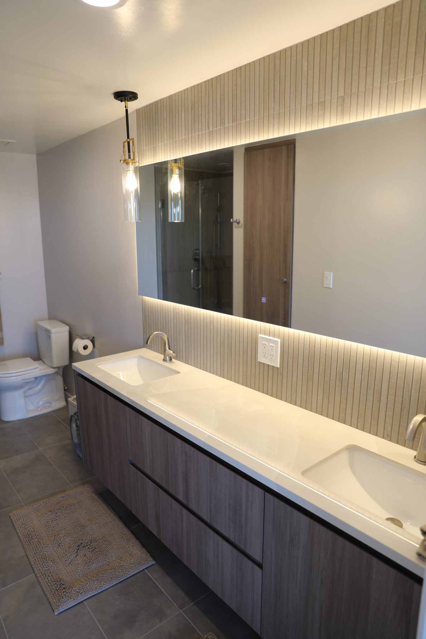 Primary bath with dual wood vanity and backlit mirror