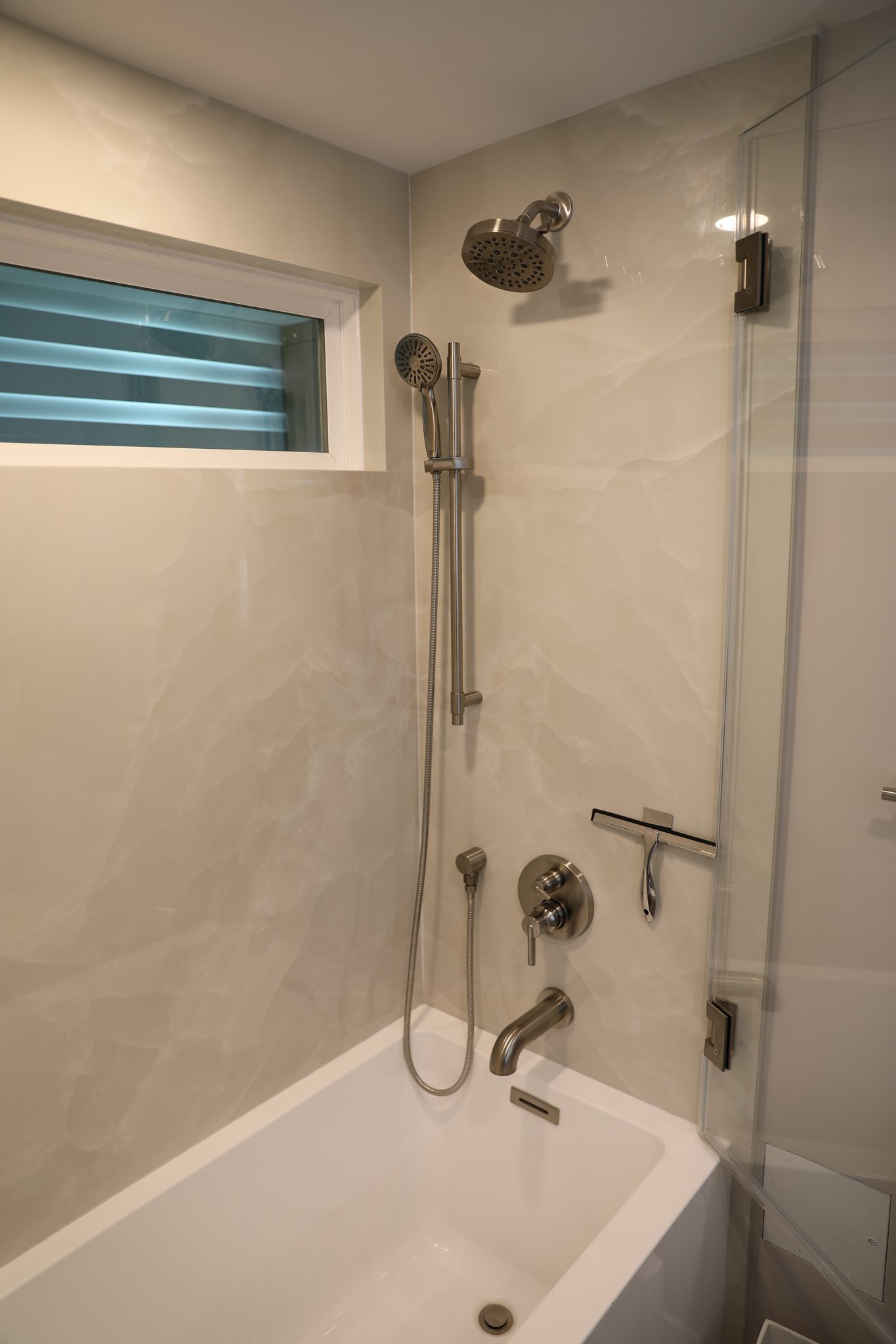 Guest shower with marble-look tile and transom