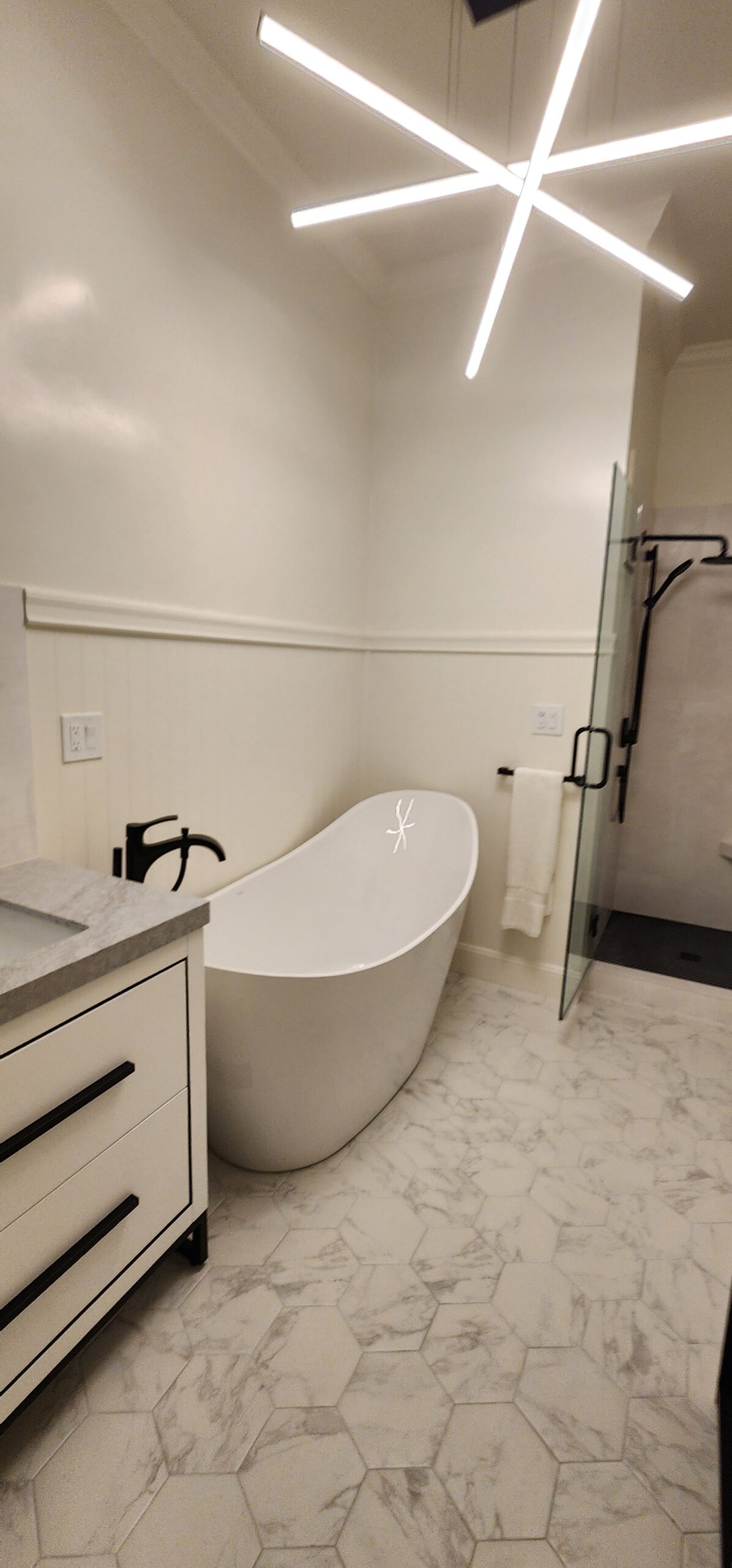 Full bathroom remodel with freestanding tub, marble hexagon tile floor, matte black fixtures, and modern light fixture in San Francisco Haight