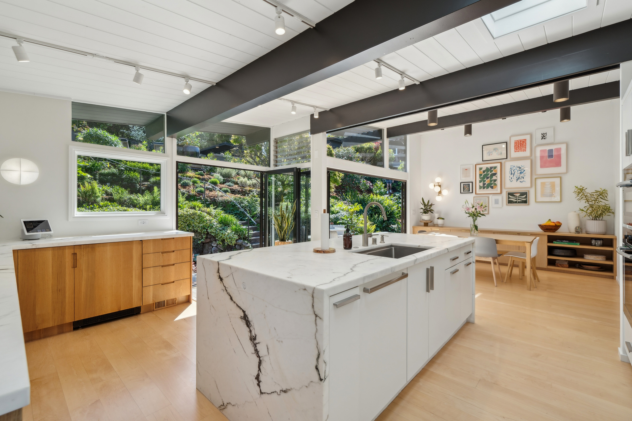 Marble waterfall island and white oak cabinets looking out to the garden