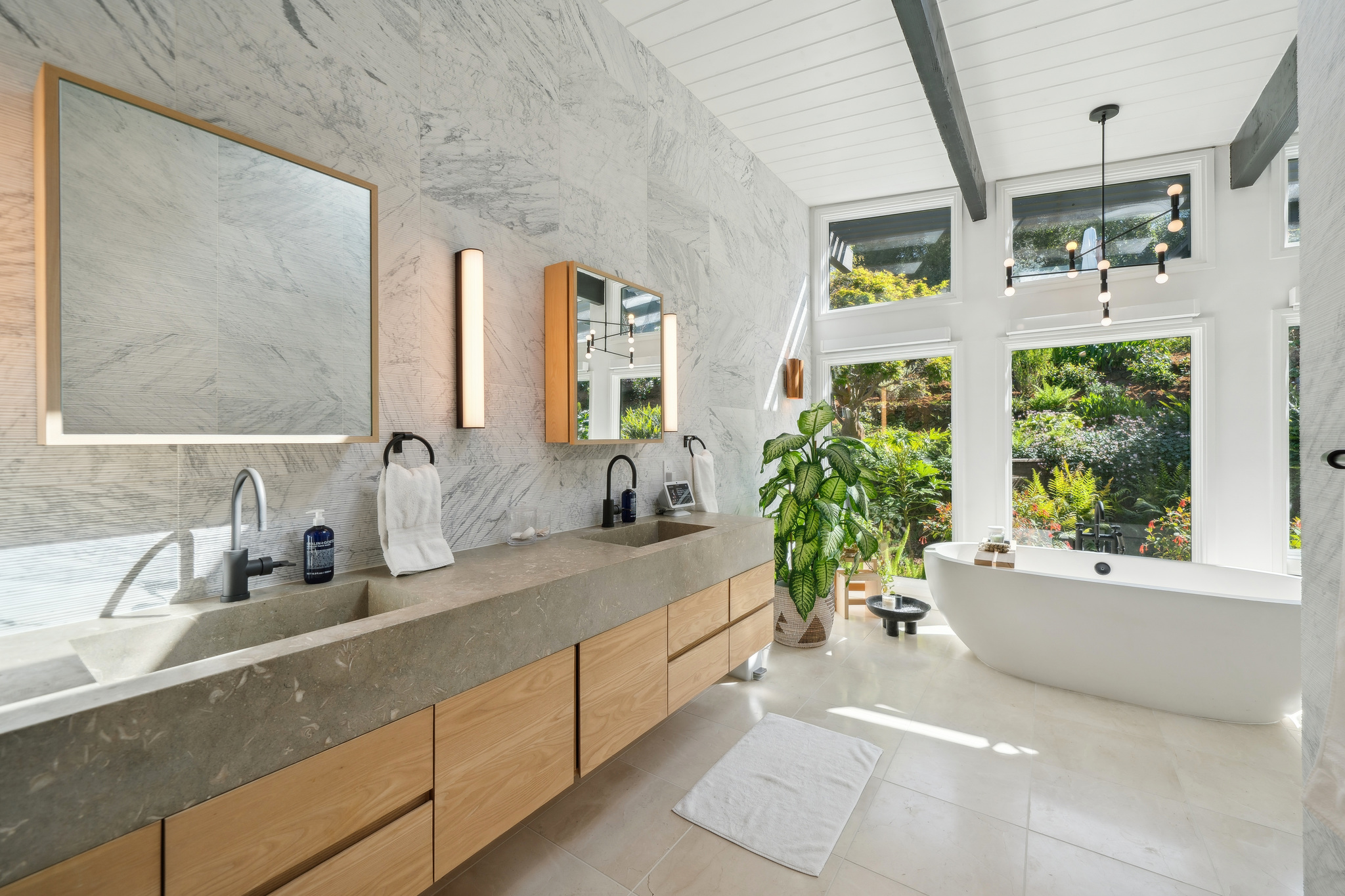 Primary bath with marble walls and wood vanities