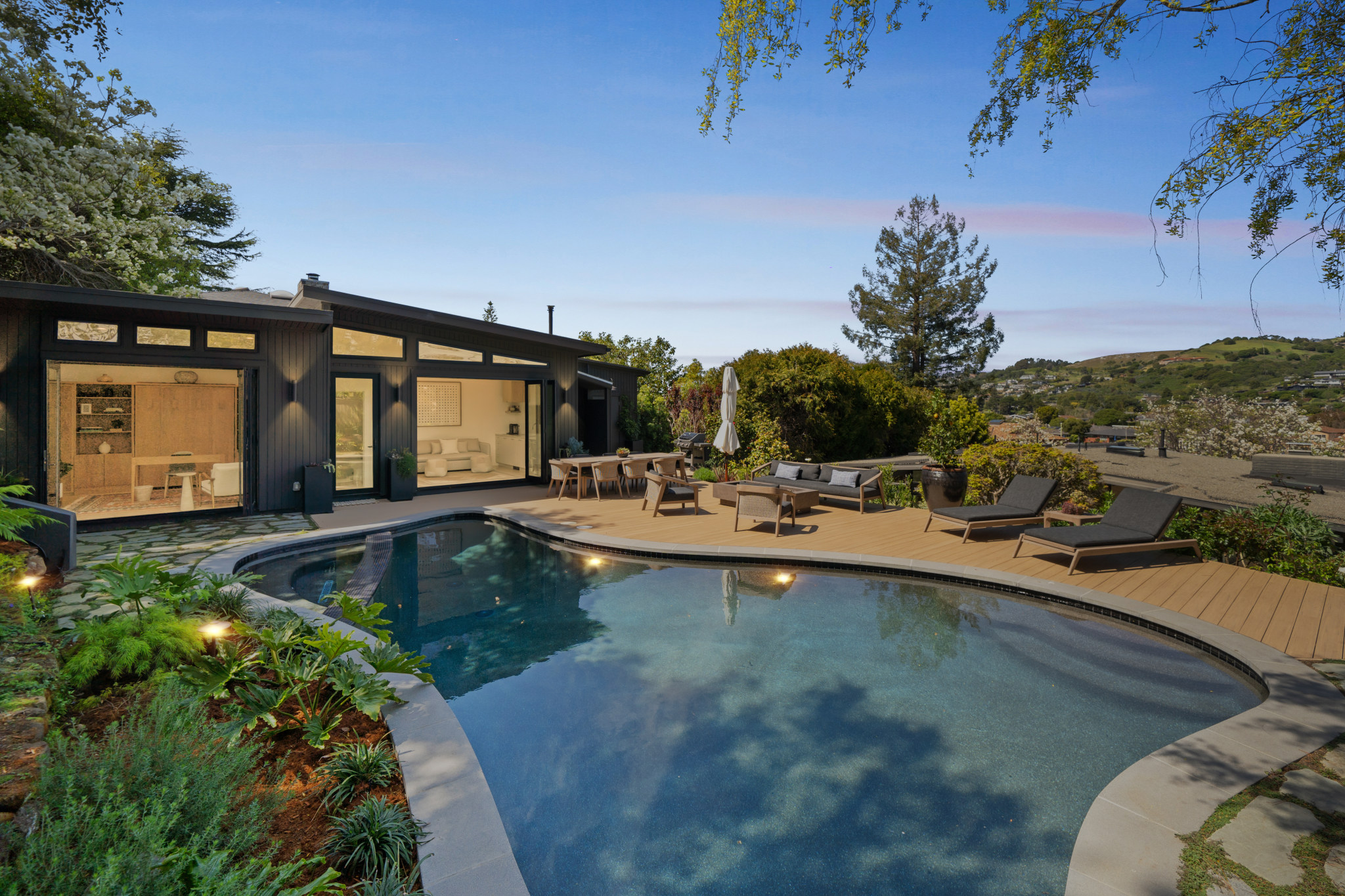 Pool terrace at dusk with the house lit